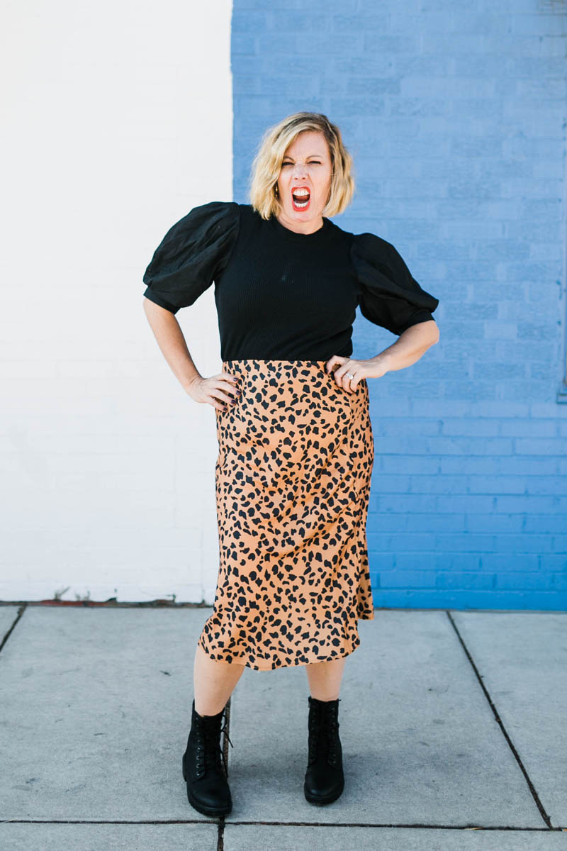 mom make roar face with hands on hips in black top with leopard skirt and combat boots
