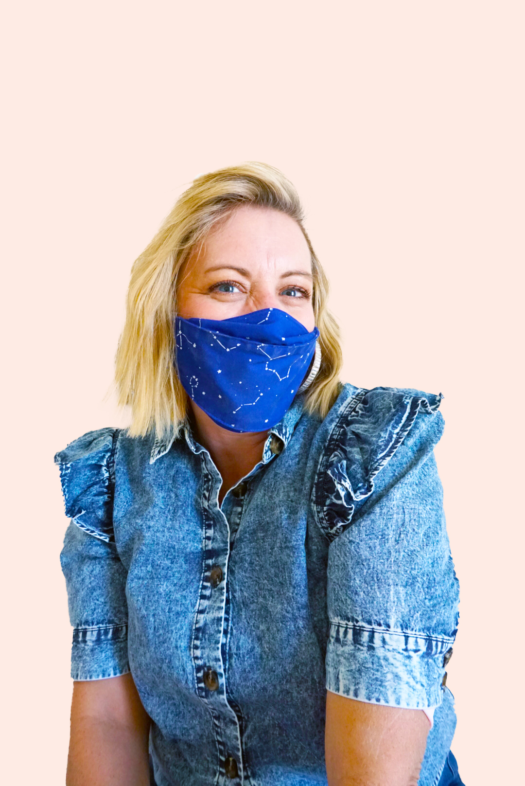 woman wearing blue star face mask against peach background